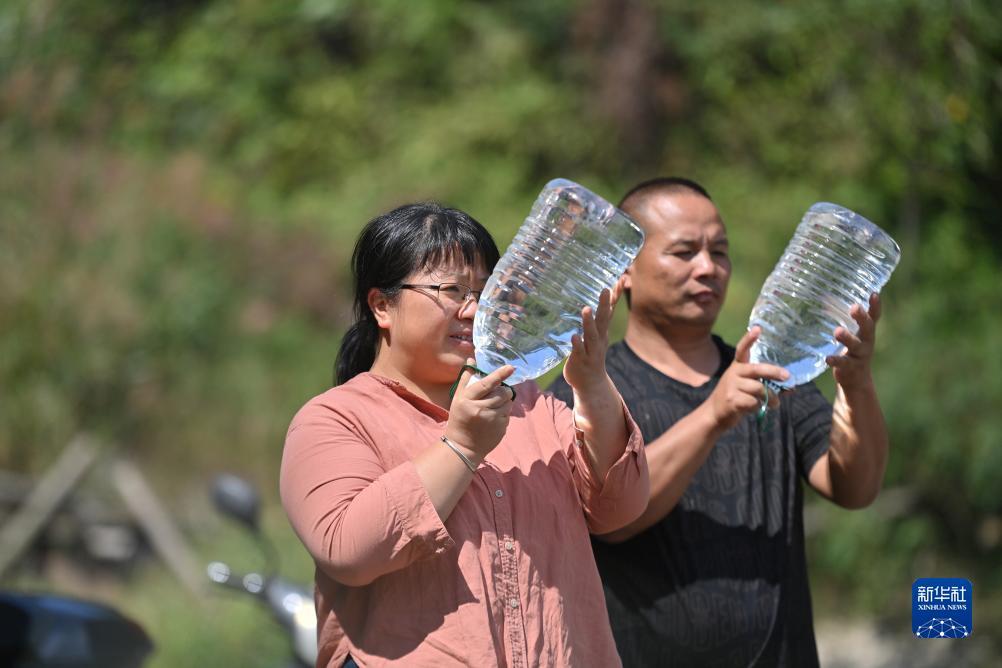 楊寧（左）在查看村民剛剛采集的水樣，為山泉水引水工程做準備（10月8日攝）。新華社記者 黃孝邦 攝